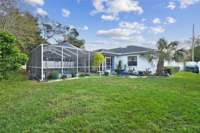 back of house with a lanai and a lawn