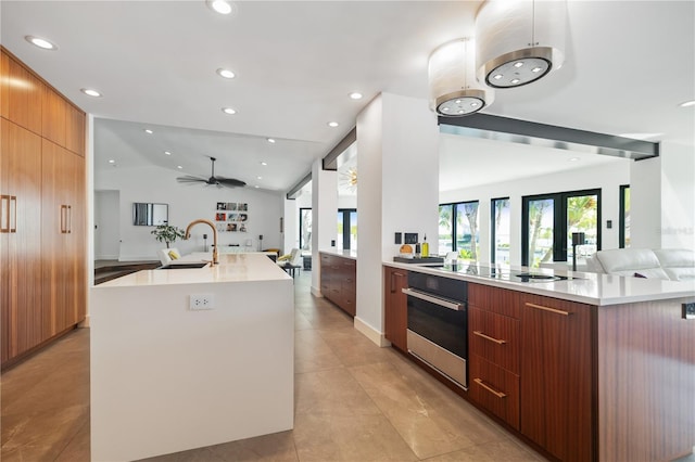 kitchen with stainless steel oven, sink, stovetop, lofted ceiling, and a large island