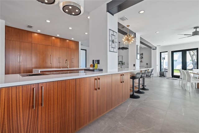 kitchen with french doors, sink, kitchen peninsula, decorative light fixtures, and a kitchen bar