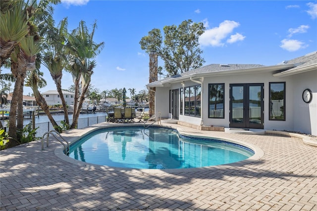 view of swimming pool with a patio area, a water view, and french doors