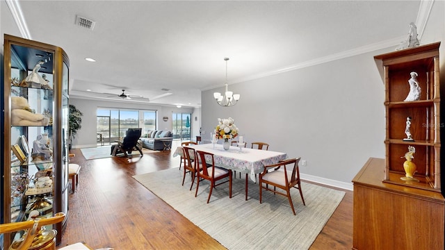 dining space with ceiling fan with notable chandelier, dark hardwood / wood-style floors, and crown molding