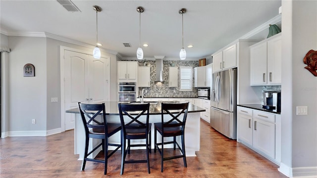 kitchen featuring stainless steel appliances, white cabinetry, a kitchen island with sink, and a breakfast bar area