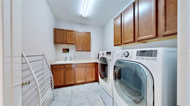 clothes washing area with sink, cabinets, separate washer and dryer, a textured ceiling, and light tile patterned floors