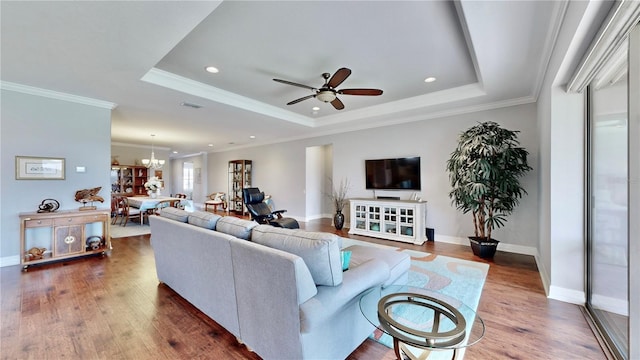 living room with a tray ceiling, ornamental molding, and dark hardwood / wood-style floors