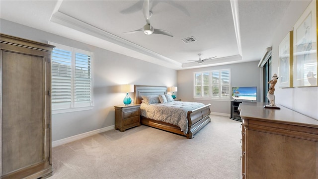 bedroom with ceiling fan, a tray ceiling, and light carpet