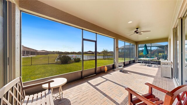 sunroom / solarium with a water view and ceiling fan