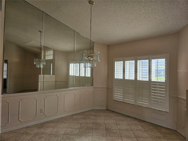 unfurnished dining area featuring a chandelier, light tile patterned floors, a textured ceiling, and lofted ceiling