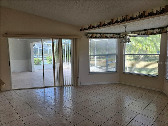 tiled empty room featuring vaulted ceiling, ceiling fan, and a textured ceiling