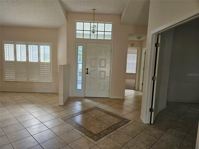 2421 E Del Webb Blvd, Sun City Center, FL 33573 - tiled entryway with a textured ceiling, a chandelier, baseboards, and a towering ceiling