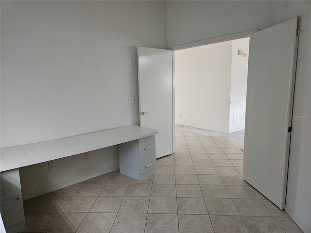 unfurnished office featuring built in desk and light tile patterned floors