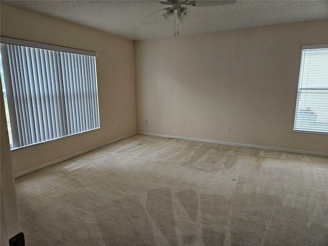 empty room featuring ceiling fan, light colored carpet, and a textured ceiling