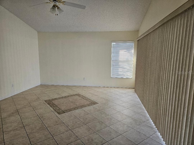 tiled spare room featuring lofted ceiling, a textured ceiling, and ceiling fan