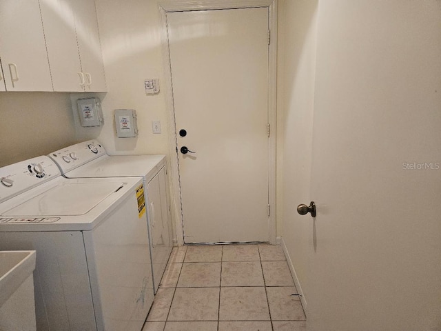 laundry room with light tile patterned floors, cabinets, and washing machine and clothes dryer