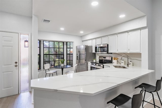 kitchen with white cabinetry, kitchen peninsula, sink, and appliances with stainless steel finishes