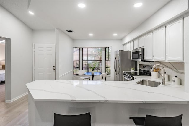 2582 Bentley Dr, Palm Harbor, FL 34684 - kitchen with a sink, appliances with stainless steel finishes, a peninsula, light wood-style flooring, and light stone counters