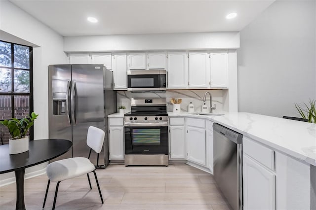 kitchen featuring white cabinets, sink, light stone countertops, tasteful backsplash, and stainless steel appliances