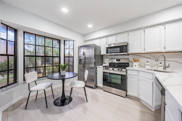 kitchen with white cabinets, sink, stainless steel appliances, and a wealth of natural light