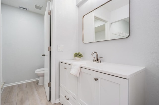 bathroom featuring vanity, wood-type flooring, and toilet