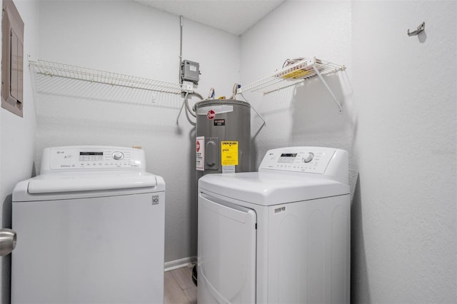 laundry area featuring light wood-type flooring, electric water heater, and washing machine and clothes dryer