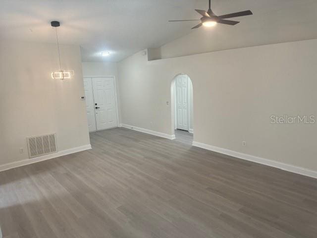 empty room with lofted ceiling, ceiling fan, and dark hardwood / wood-style floors