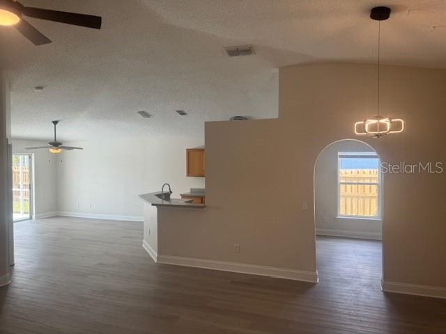 empty room with ceiling fan with notable chandelier, a textured ceiling, dark hardwood / wood-style flooring, and high vaulted ceiling