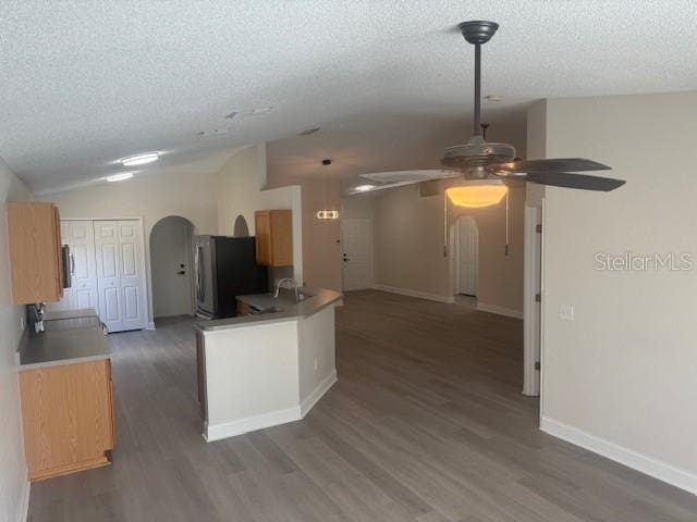 kitchen featuring lofted ceiling, a textured ceiling, kitchen peninsula, dark hardwood / wood-style floors, and stainless steel fridge