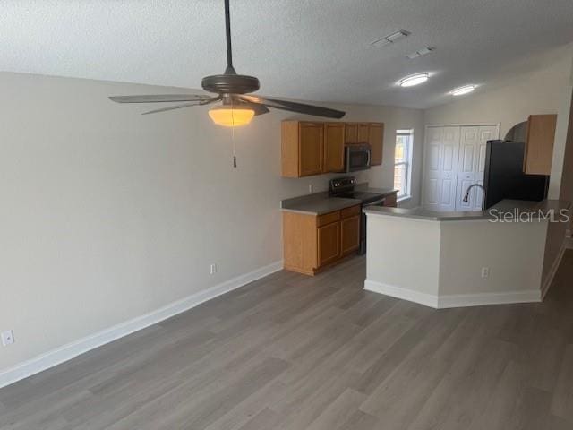 kitchen with a textured ceiling, hardwood / wood-style flooring, and black appliances