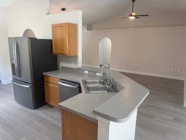 kitchen featuring vaulted ceiling, sink, appliances with stainless steel finishes, and light hardwood / wood-style floors