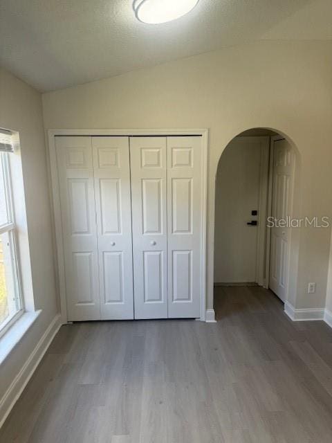 unfurnished bedroom featuring wood-type flooring, a closet, and lofted ceiling