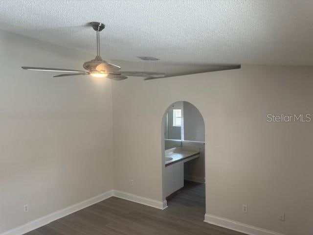 empty room featuring ceiling fan, dark hardwood / wood-style flooring, and a textured ceiling