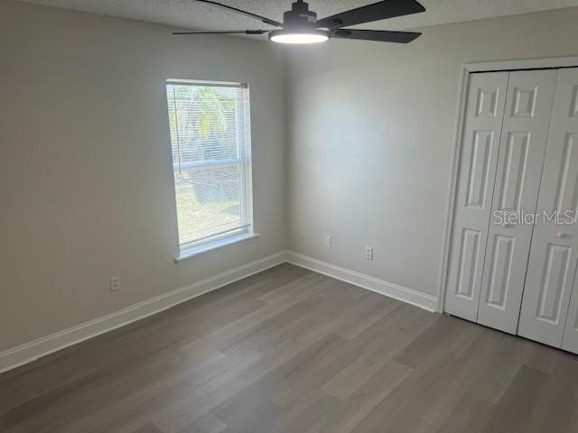 unfurnished bedroom featuring multiple windows, light wood-type flooring, a closet, and ceiling fan