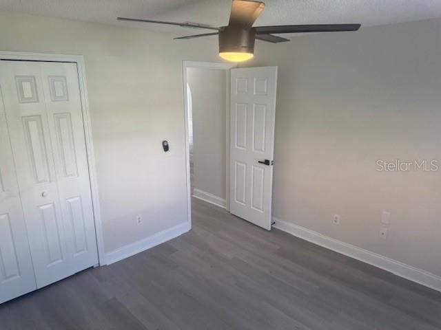 unfurnished bedroom featuring ceiling fan, a closet, and dark wood-type flooring