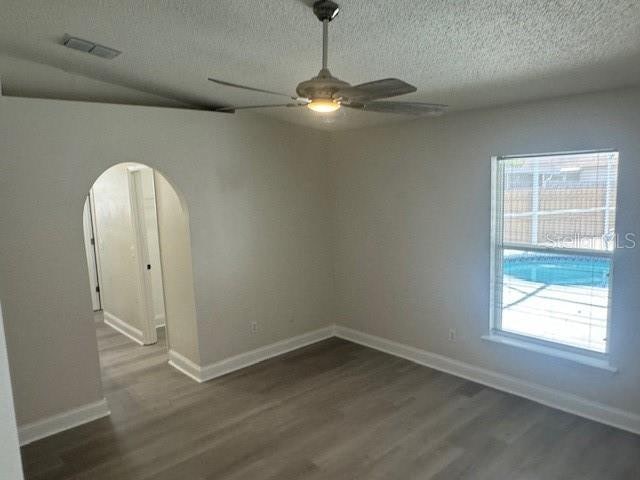 spare room with a textured ceiling, dark hardwood / wood-style floors, ceiling fan, and lofted ceiling