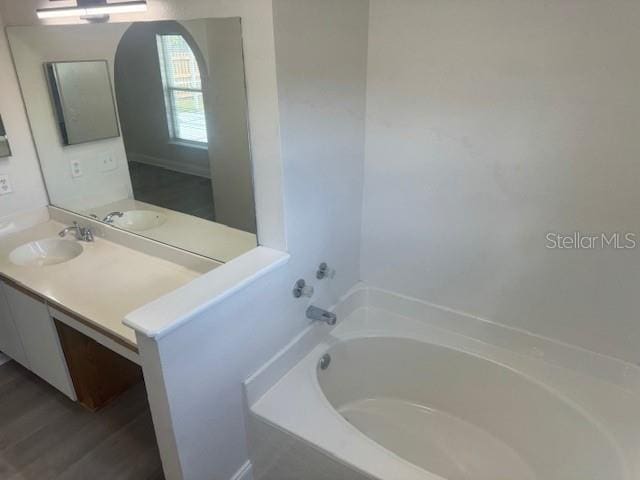 bathroom featuring vanity, hardwood / wood-style flooring, and a bathing tub