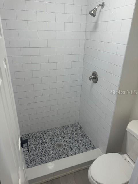 bathroom with toilet and a tile shower