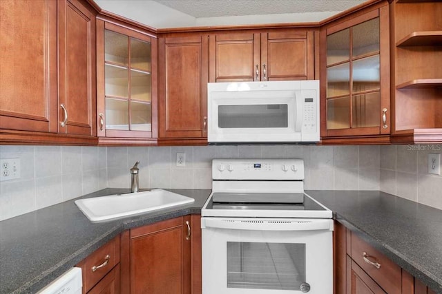 1127 Pine Ridge Cir W Unit A2, Tarpon Springs, FL 34688 - kitchen with white appliances, a sink, brown cabinetry, dark countertops, and backsplash