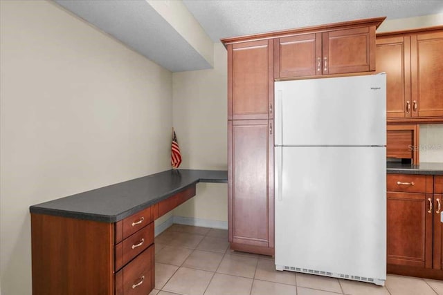 1127 Pine Ridge Cir W Unit A2, Tarpon Springs, FL 34688 - kitchen with freestanding refrigerator, dark countertops, light tile patterned floors, and brown cabinetry