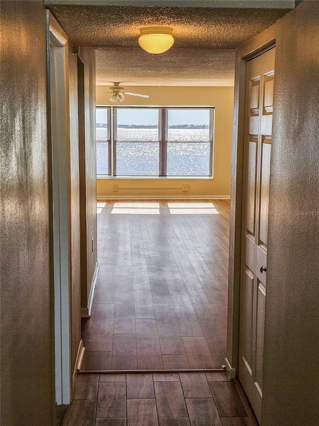 corridor with dark hardwood / wood-style flooring and a textured ceiling