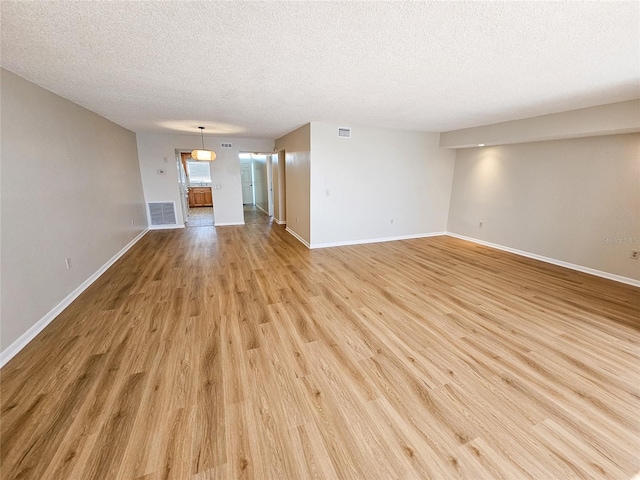 unfurnished living room featuring a textured ceiling and light hardwood / wood-style flooring