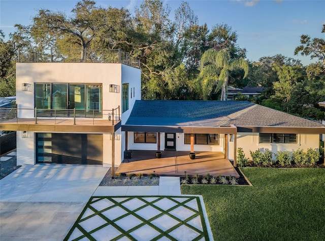 modern home with a front yard, a balcony, and a garage