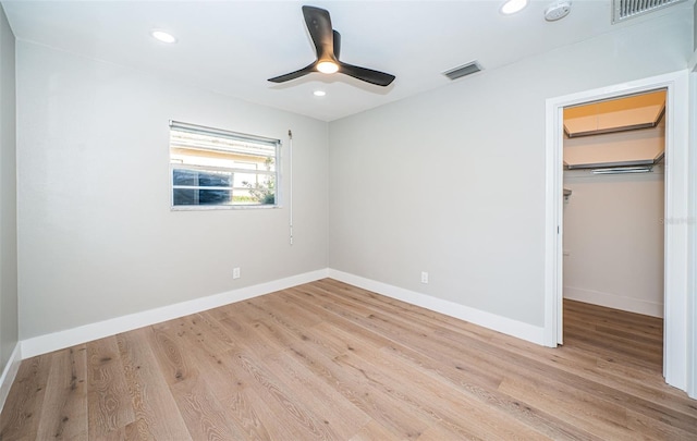 unfurnished bedroom featuring light wood-type flooring, a closet, a spacious closet, and ceiling fan