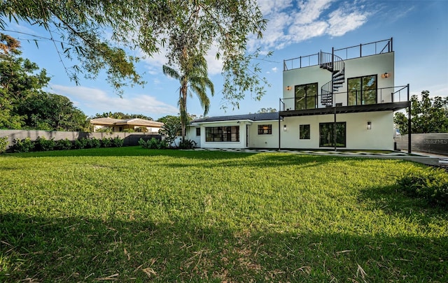 rear view of house with a yard and a balcony