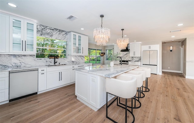 kitchen featuring light stone counters, white appliances, a kitchen island with sink, sink, and white cabinets