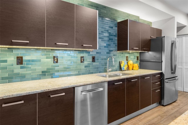 kitchen featuring appliances with stainless steel finishes, light hardwood / wood-style flooring, dark brown cabinets, and sink