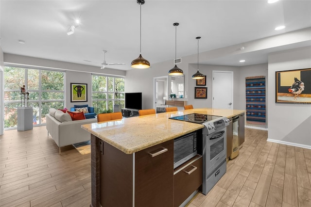 kitchen featuring light hardwood / wood-style flooring, ceiling fan, a center island, and pendant lighting