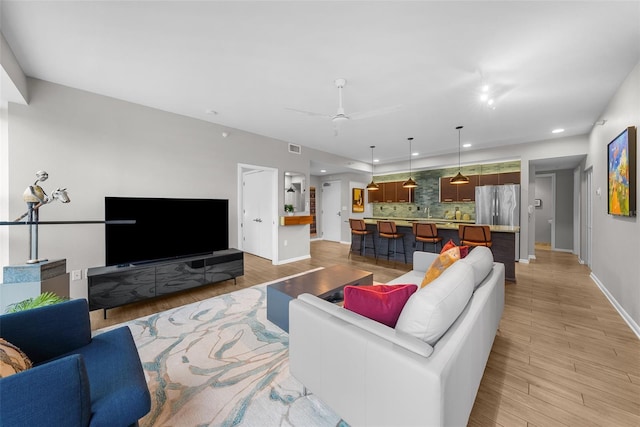 living room with ceiling fan and light hardwood / wood-style floors