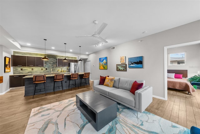 living room featuring ceiling fan and light wood-type flooring