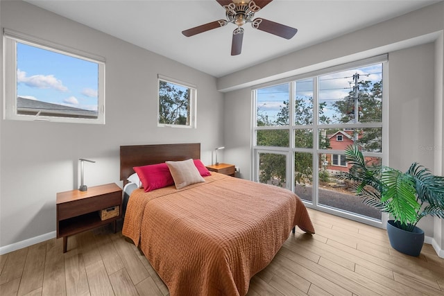 bedroom featuring light hardwood / wood-style flooring, multiple windows, and ceiling fan