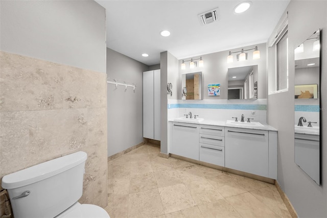 bathroom featuring vanity, tile walls, and toilet