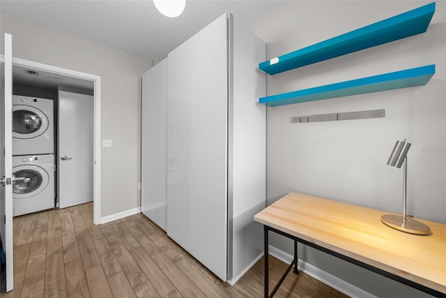 laundry room with stacked washer / drying machine and light hardwood / wood-style flooring